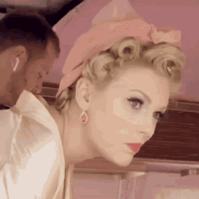 a woman is getting her hair done by a man while wearing a pink headband .
