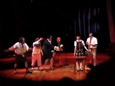 a group of people are dancing on a stage and one of them is wearing a shirt that says l