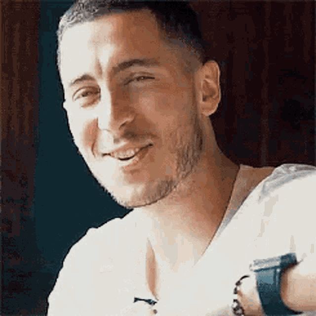 a close up of a man with a beard wearing a white shirt and a watch .
