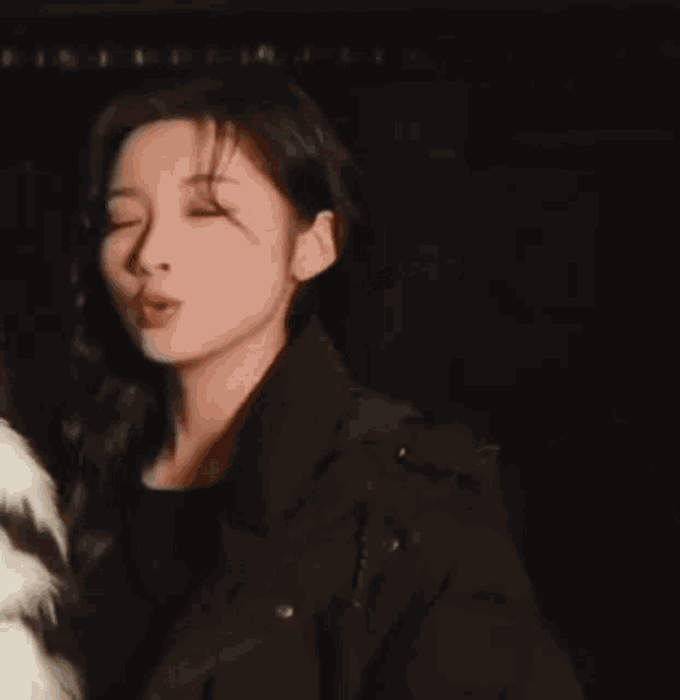 a woman wearing a black jacket and a white fur coat