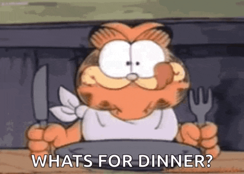 garfield is holding a knife and fork while sitting at a table .
