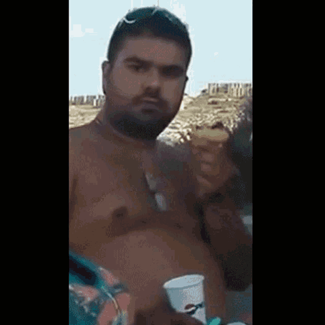 a shirtless man is holding an ice cream cone