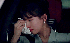 a woman is sitting in the driver 's seat of a car holding a napkin to her nose .