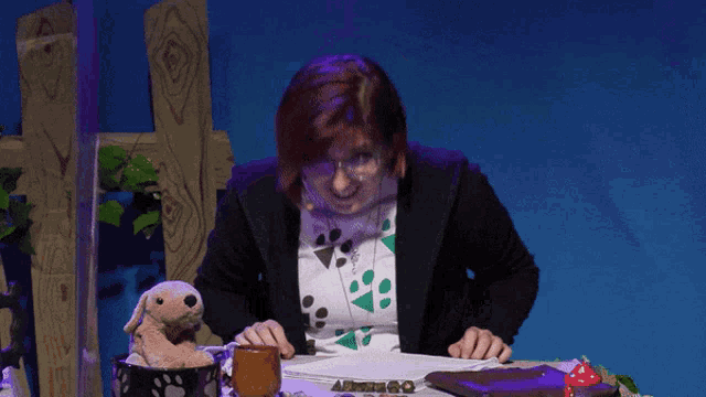 a woman sitting at a table with a dog in a basket and a bible