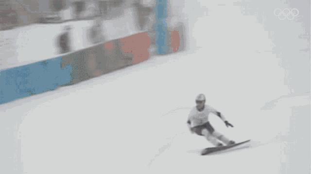 a blurred image of a person riding a snowboard with the olympics logo in the background