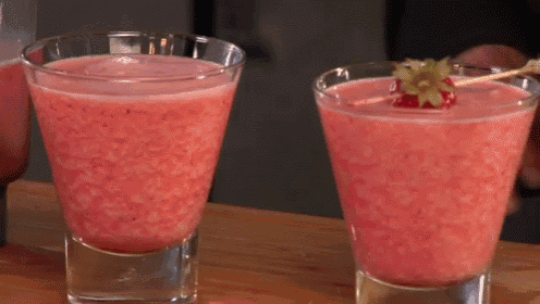 two glasses of pink liquid with a strawberry on a stick