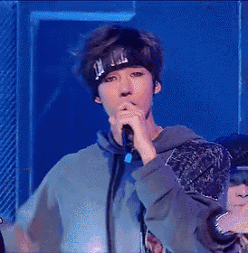 a man wearing a headband is singing into a microphone while wearing a hoodie