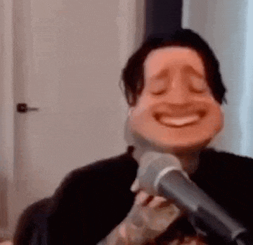 a man is singing into a microphone with a funny face .