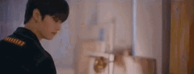 a young man in a suit is standing in a room looking at something .