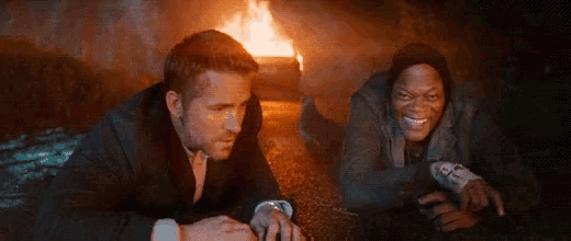 a man and a woman are laying on the ground in front of a fire .