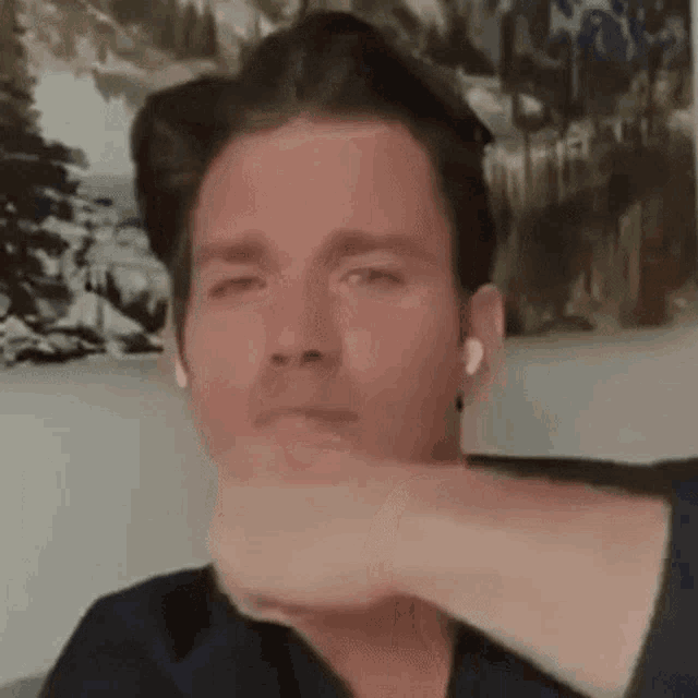 a man wearing ear buds is sitting on a couch with his hand on his face .