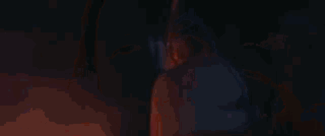 a close up of a woman 's face in a dark room with a red and blue light behind her .