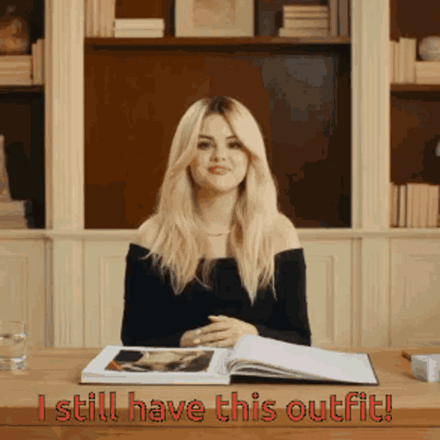 a woman sitting at a desk with a book and the words " i still have this outfit " above her