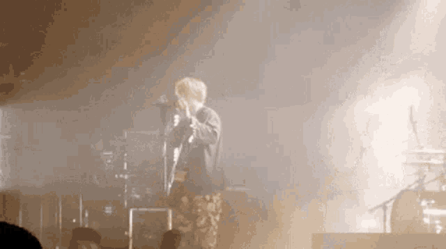a man singing into a microphone on a stage in front of a crowd