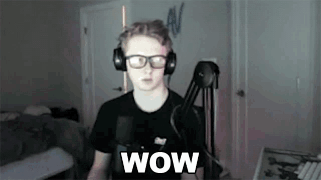 a young man wearing headphones and glasses is standing in front of a microphone and says wow .