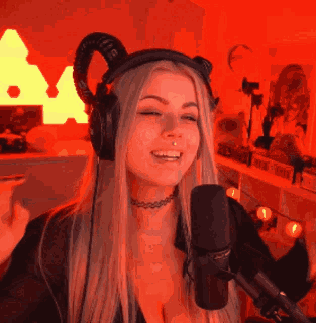 a woman wearing headphones and a choker is smiling into a microphone