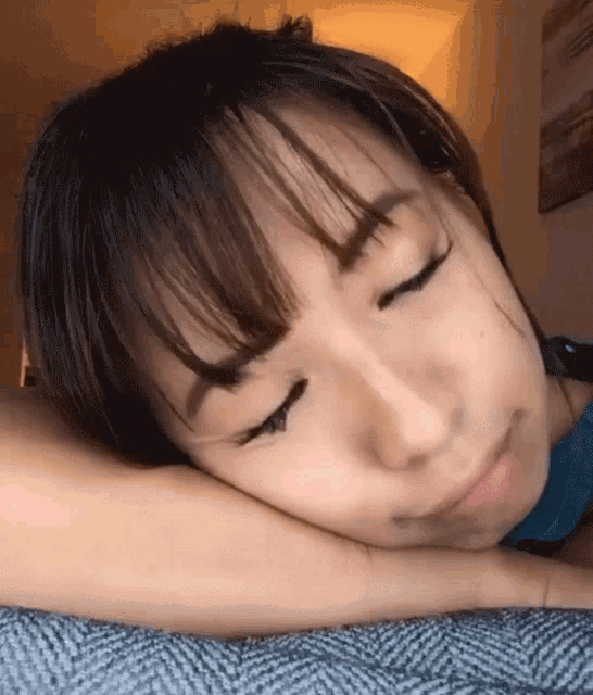 a woman laying down with her eyes closed and her head resting on her arm