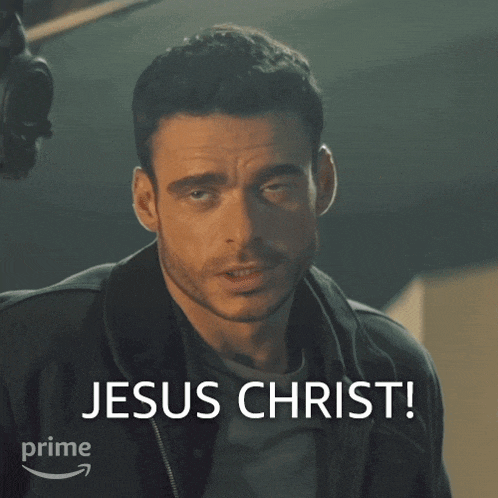 a man in a black jacket says " jesus christ " in front of him