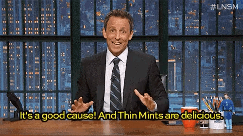 a man in a suit and tie is sitting at a desk talking about thin mints