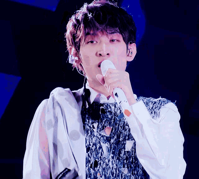 a young man singing into a microphone with a white shirt that says ' i love you ' on the sleeve