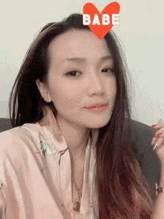a woman is wearing a heart with the word babe written on it