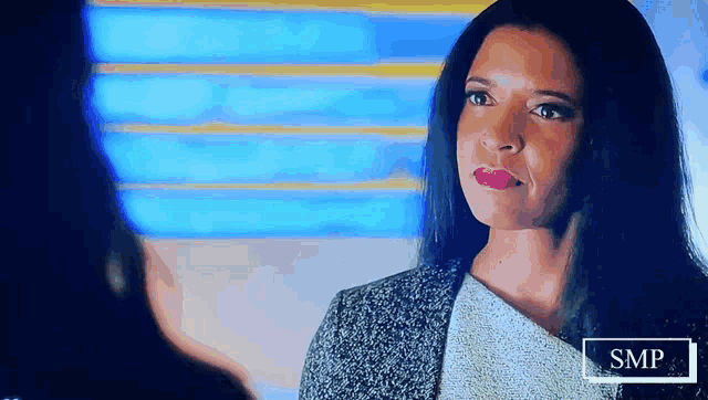 a woman is looking at another woman in front of a sign that says smp on it