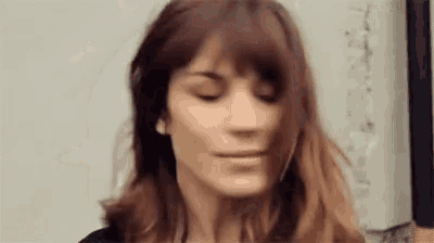 a woman with long brown hair is making a funny face with her eyes closed .