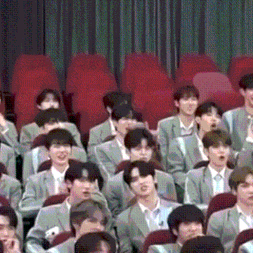 a large group of people are sitting in red chairs in a theatre .