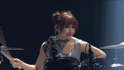 a woman playing a drum set with a microphone attached to her ear
