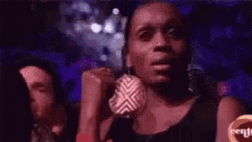 a woman is sitting in a dark room with her fist up .