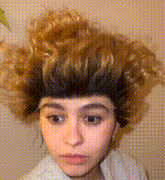 a woman with a wig on her head looks at the camera with a serious look on her face