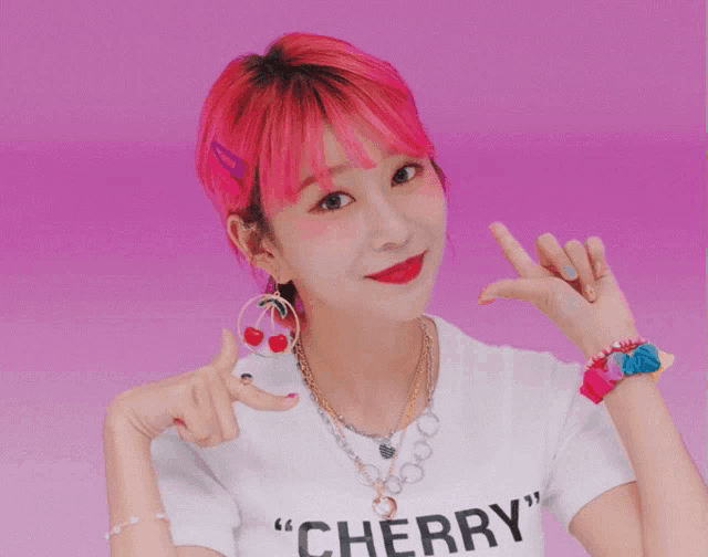 a girl with pink hair is wearing a shirt that says " cherry "