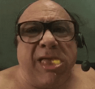 a bald man wearing glasses and a headset is eating a yellow object .