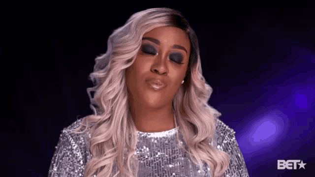 a woman wearing a silver sequined dress is making a funny face