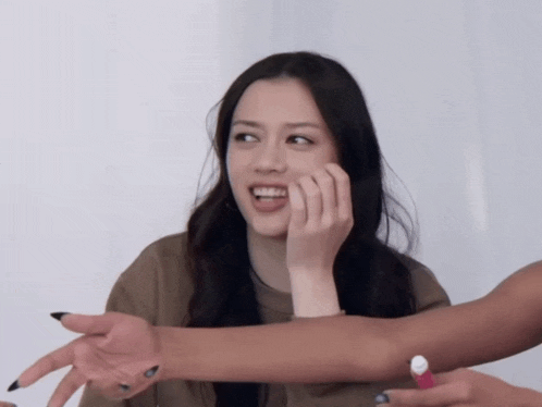 a woman with long black nails is smiling while holding her hand to her face