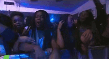 a group of young women are dancing at a concert and one of them is giving the middle finger .