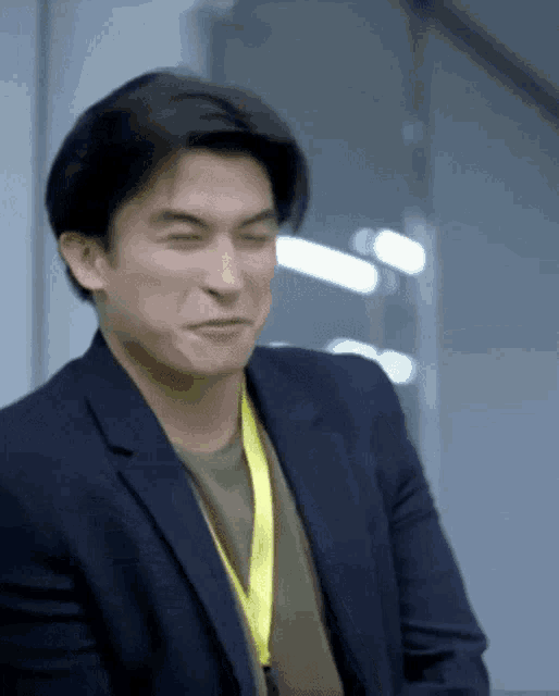 a man in a suit and a yellow lanyard making a funny face