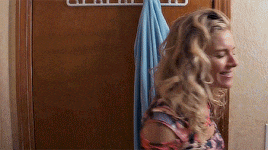 a woman standing in front of a door with a towel hanging on it .