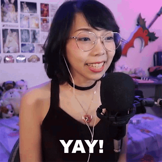 a woman wearing glasses and headphones is smiling and saying yay .