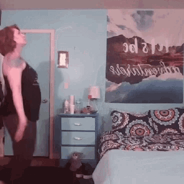 a woman is dancing in a bedroom with a painting on the wall that says ' sdl ' on it