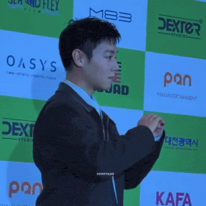 a man in a suit stands in front of a wall that says oasys and pan