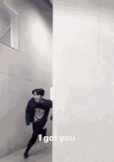 a man is running through a hallway next to a wall and says `` i got you '' .