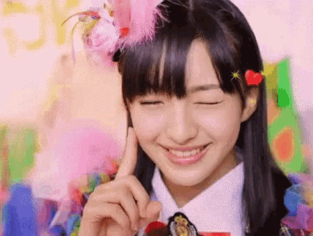 a girl wearing a pink flower in her hair is smiling with her eyes closed