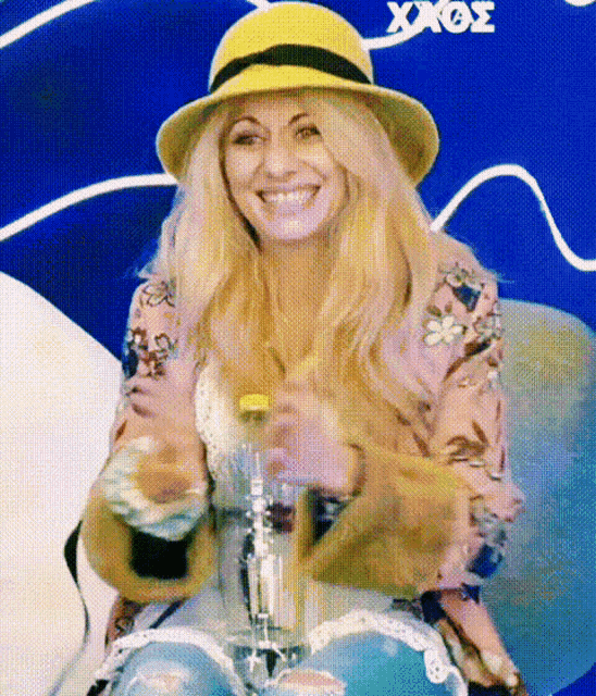 a woman wearing a yellow hat is smiling and holding a bottle of soda