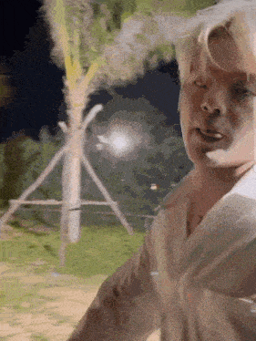a man is standing in front of a palm tree and looking at the camera