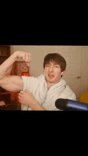 a man is flexing his muscles in front of a microphone