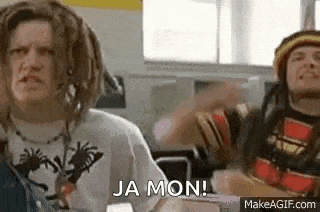 a man with dreadlocks is sitting at a desk in a classroom with another man .