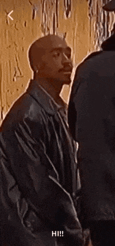 a man in a leather jacket is standing next to another man and talking to him .