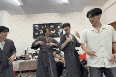 a group of young men are dancing in a room with a picture of birds on the wall