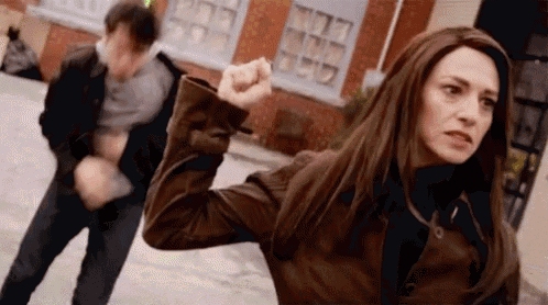 a woman is holding a fist up in front of a man in a leather jacket .